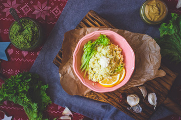 Cauliflower vegan vegetarian rice salad with fresh salad leaves in  bowl with spinach avocado sauce on red Christmas tablecloth. Healthy lunch or dinner
