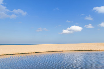 Landscape view of empty tropical Mai Khao beach and blue sea under blue sky