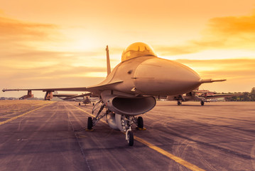 Fototapeta na wymiar fighter jet military aircraft parked on runway standby ready to take off on sunset