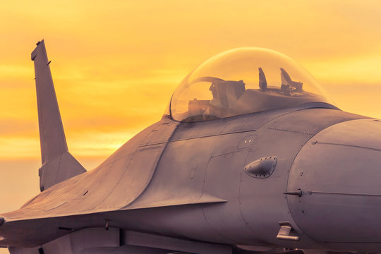 military jet aircraft parked on runway  standby ready to take off  in sunset
