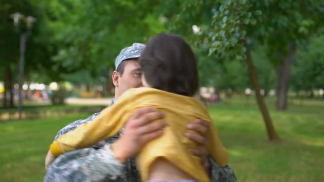 Happy american soldier hugging son, boy waving national flag, patriot homecoming