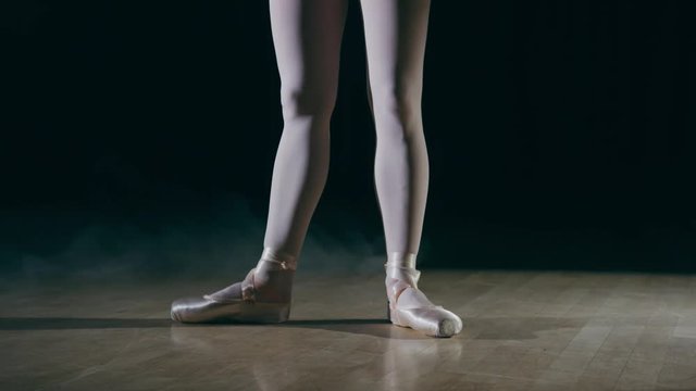 Female ballet dancer very athletic and flexible spot light hazy room  performing and streching