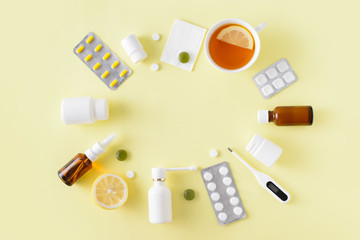 Cold and flu treatment set. Pills, throat spray, medical mask, thermometer, recipe on simple yellow background. Health care therapy. Flat lay, top view. Frame with free copy space.