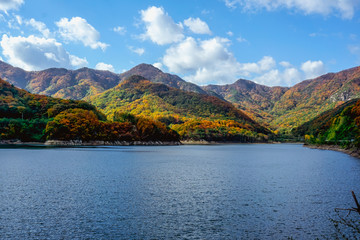 Fototapeta na wymiar Beautiful mountain lake in the valley of the hills, in autumn, among thousands of colorful trees. Iwon Village, South Korea