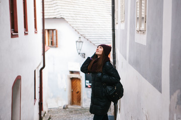 Fototapeta na wymiar Tourist girl on a beautiful street in Cesky Krumlov in the Czech Republic while traveling around the city is looking at sightseeing places or she is lost.