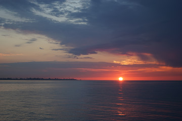 Fototapeta premium Amazing sunset on the ocean. View of dramatic cloudy sky and reflection of the sunlight on water.