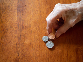 Elderly Woman's Wrinkled Hand Stacking Pennies, Nickels and Dimes