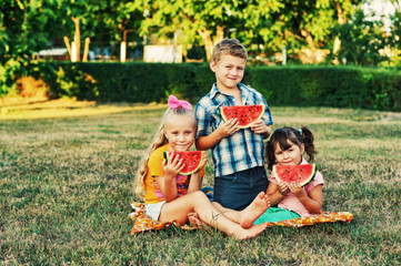 Children with watermelon in nature . Friends on a picnic eating watermelon .