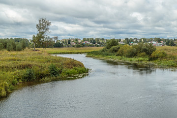 The river with green banks under a cloudy sky