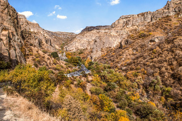 View of the rocks of the Geghama ridge covered with autumn forest and the road with pilgrims leading to the Geghard monastery in Armenia
