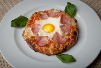 egg and ham pizza on a white plate