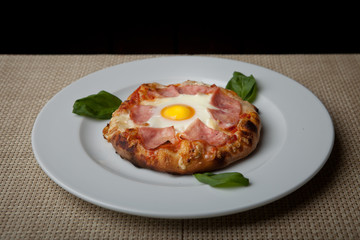 egg and ham pizza on a white plate