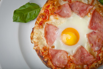 egg and ham pizza on a white plate