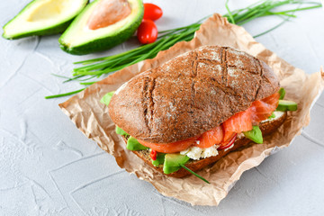 sandwich with avocado and salmon on a light background, green onions and gluten-free grain bread, radishes and tomatoes. concept diet food, copy space, sandwich take away, healthy fast food