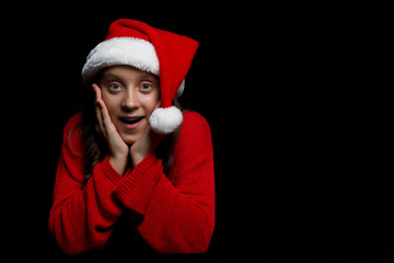 Merry Christmas. The young girl in a red sweater and Santa's hat