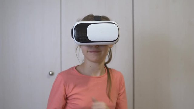 Teen girl wears her virtual reality headset and joyfully virtual world.
