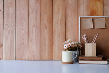 Workspace with copy space coffee mug, flower, wood board and sticky note with pencil on office desk.