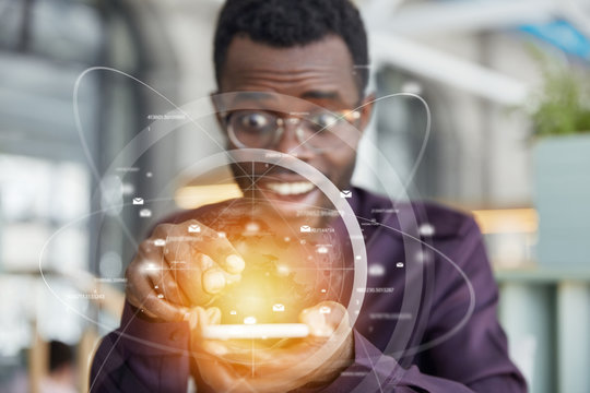 Horizontal shot of glad black man owns business company, recieves text message on mobile phone with double exposure, interface, involved in trading, has joyful expression. Modern technologies concept