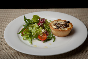 julienne in tartlet with salad and tomatoes on a white plate