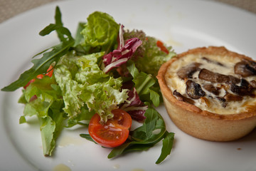 julienne in tartlet with salad and tomatoes on a white plate