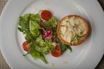 julienne in tartlet with salad and tomatoes on a white plate