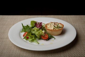 julienne in tartlet with salad and tomatoes on a white plate
