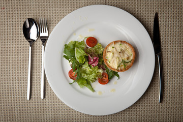 julienne in tartlet with salad and tomatoes on a white plate