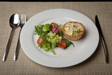 julienne in tartlet with salad and tomatoes on a white plate