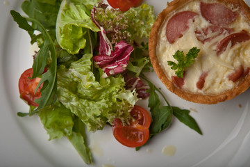 julienne in tartlet with salad and tomatoes on a white plate