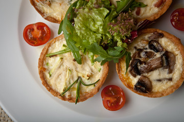 julienne in tartlet with salad and tomatoes on a white plate