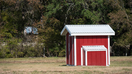Fototapeta na wymiar Small red and white shed in grassy field
