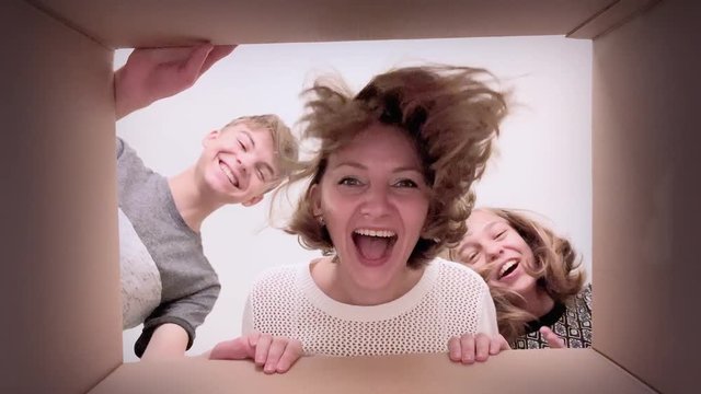 Happy family - mom, son and daughter opening present cardboard box and looking inside. Woman and children unboxing gift - different emotions. Concept of holidays Christmas, Birthday or New Year