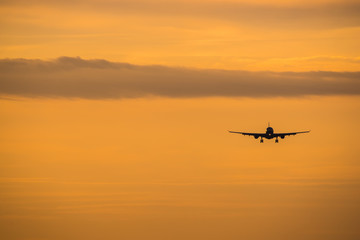 Fototapeta na wymiar Dramatic view of a dark silhouette of aircraft against a orange sunset sky