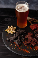 Assorted snacks, jerky on circle stone board with cold beer