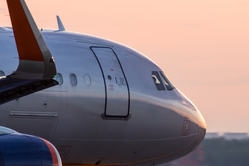 Fototapeta na wymiar Modern civil airplane nose closeup view during sunrise.