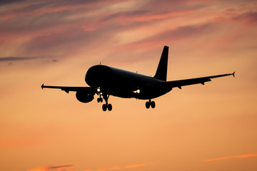 Dramatic view of a dark silhouette of aircraft against a orange sunset sky