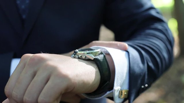 The wrist of a businessman in a suit, shows the clock. It's time to quickly do business.