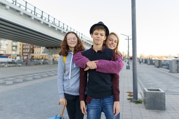 Outdoor city portrait of three friends teen boys and girls 13, 14 years old