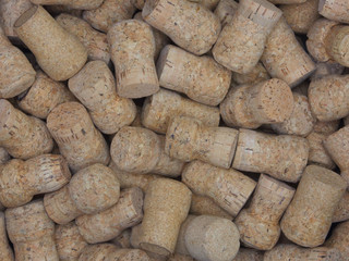 A large collection of natural champagne or sparkling wine corks, is shown in a loosely stacked pile.