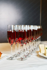 rows of red champagne and sparkling wine glasses at banquet night time party new year corporate party concept