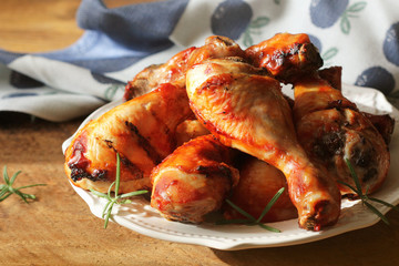 Grilled chicken legs with rosemary served on white plate. Dinner background