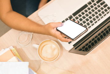 Asian young woman drinking coffee while reading electronic book with her smartphone and laptop..