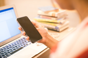 Asian young woman drinking coffee while reading electronic book with her smartphone and laptop..
