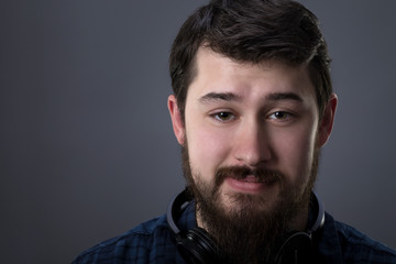 portrait of a bearded guy with headphones,  cute smiling on gray background