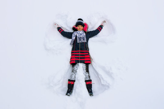 The girl lies in the snow and makes a snow angel