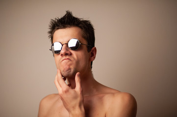 Attractive swimmer. Studio shot of a young shirtless athlete on a gray background. Man with glasses