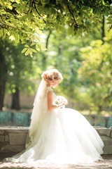 Fototapeta na wymiar Beautiful blonde bride with stylish make-up in white dress with wedding bouquet