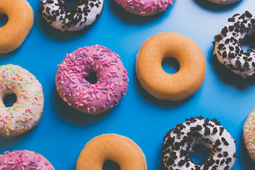 Top view of many colorful donuts on blue background.