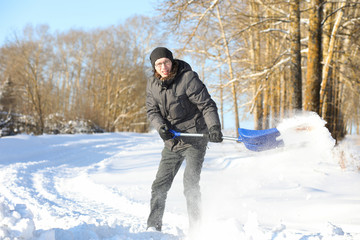 man remove snow with shovel from the road in winter