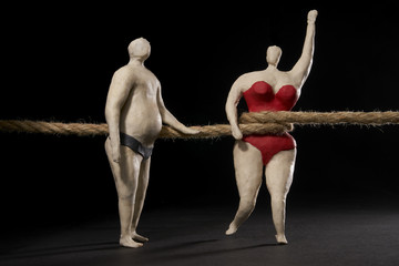 Large rope tightens the waist of a fat woman in front of a big man with a big belly. Isolated on...